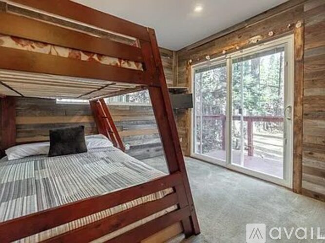 A bedroom with a bunk bed and a window with a view of trees.