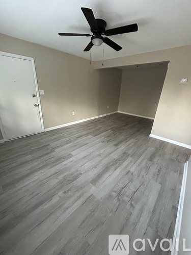 A room with a ceiling fan and wooden flooring.