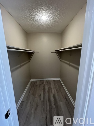 A white door is open to a small closet with two shelves.
