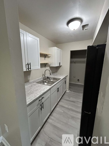 A kitchen with white cabinets and a black refrigerator.
