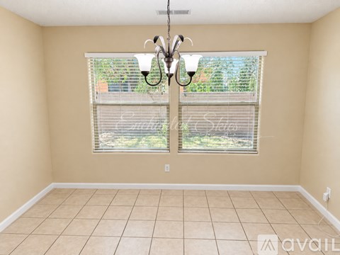 A room with a chandelier, tiled floor, and a window with blinds.