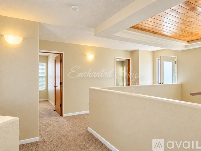 A spacious room with a carpeted floor and a wooden ceiling.