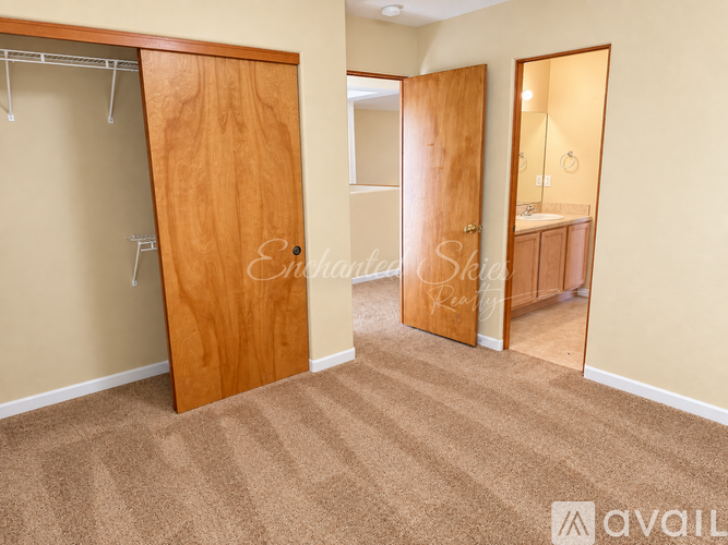 A bedroom with a wooden door and carpeted floor.