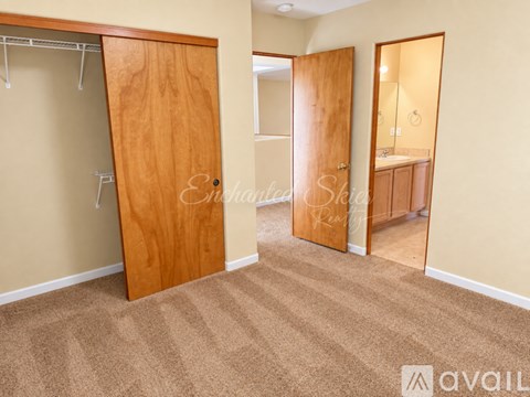 A bedroom with a wooden door and carpeted floor.