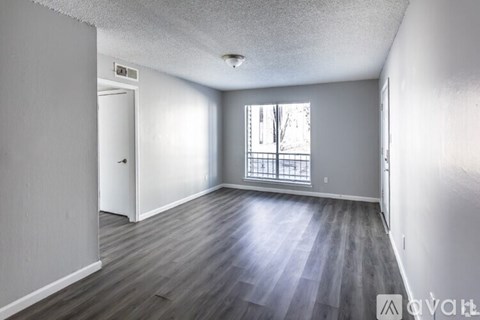 A spacious room with wooden flooring and a large window.