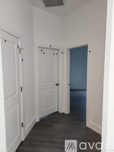 A hallway with two doors and a wall with blue tape on it.