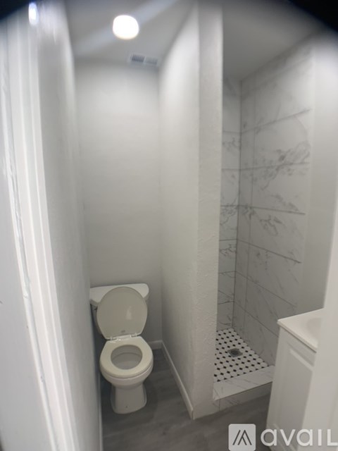 A white toilet in a small bathroom with a tiled shower area.