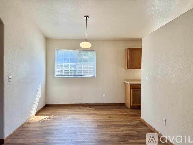A room with wooden floors and a window with a view of a building outside.