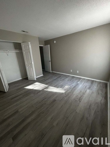 A room with wooden flooring and two open doors.
