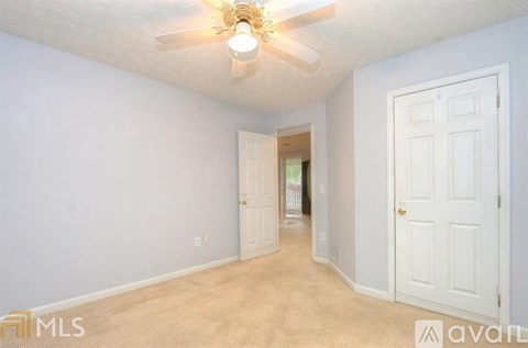 A room with a ceiling fan and two doors.