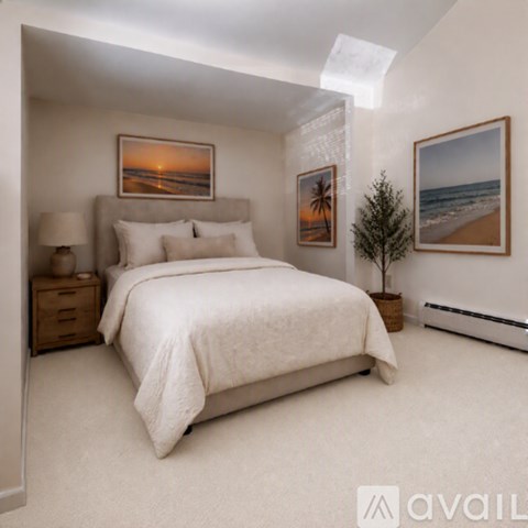 A bedroom with a large bed, a lamp, and two pictures on the wall.