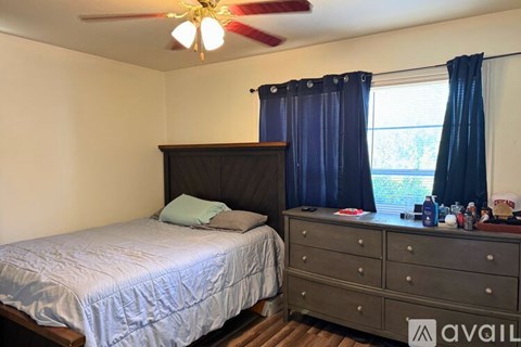 A bedroom with a bed, dresser, and window.