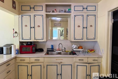 A kitchen with blue and white cabinets and a red microwave.