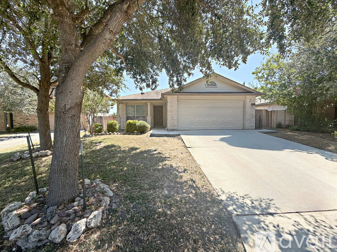 A residential house with a driveway and a tree in front.