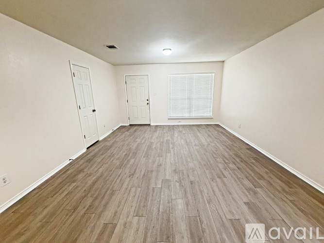 A room with wooden flooring and two doors.