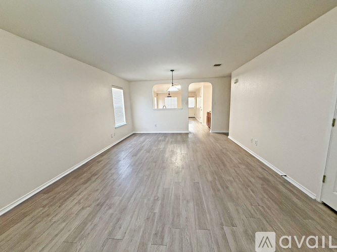 A spacious room with wooden flooring and white walls.