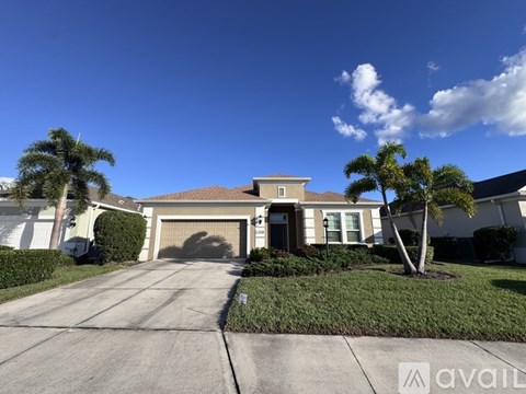 A house with a driveway and palm trees in front.