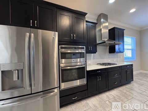 A modern kitchen with black cabinets and stainless steel appliances.