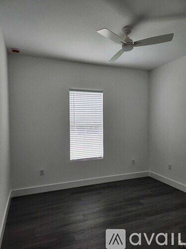 A room with a ceiling fan and a window with blinds.