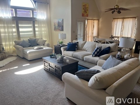 A living room with white furniture and a large window.