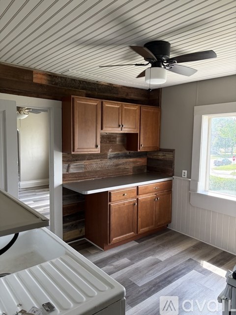 A kitchen with wooden cabinets and a ceiling fan.