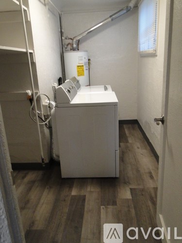 A white industrial machine sits in a room with wood flooring.