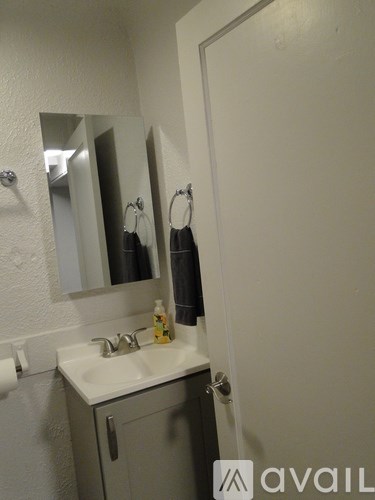 A bathroom with a sink, mirror, and towel rack.