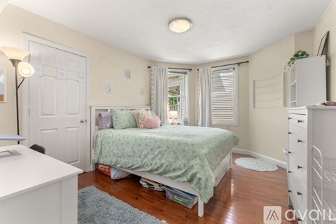 A bedroom with a bed, nightstand, and window.