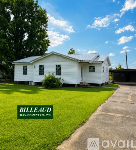 A white house with a green lawn and the words "Billeaud Management Co., Inc." on the sign.