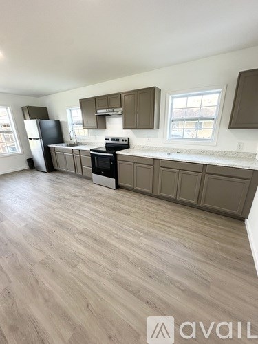 A kitchen with wooden floors and a black fridge.