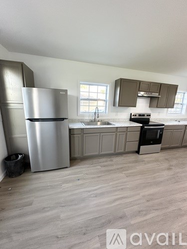 A kitchen with a stainless steel refrigerator and a black trash can.