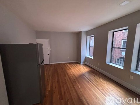 A room with wooden floors and a refrigerator.