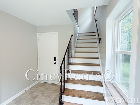 A staircase with a black railing and wooden steps leading to a white door.