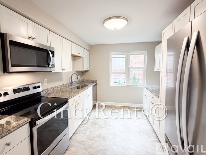 A kitchen with white cabinets and a black microwave.