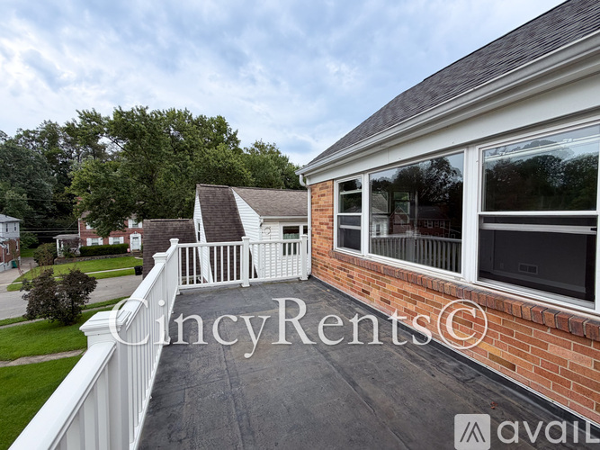 A white deck with a railing and a brick building with a window.