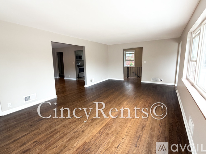 A spacious room with wooden floors and a large window.