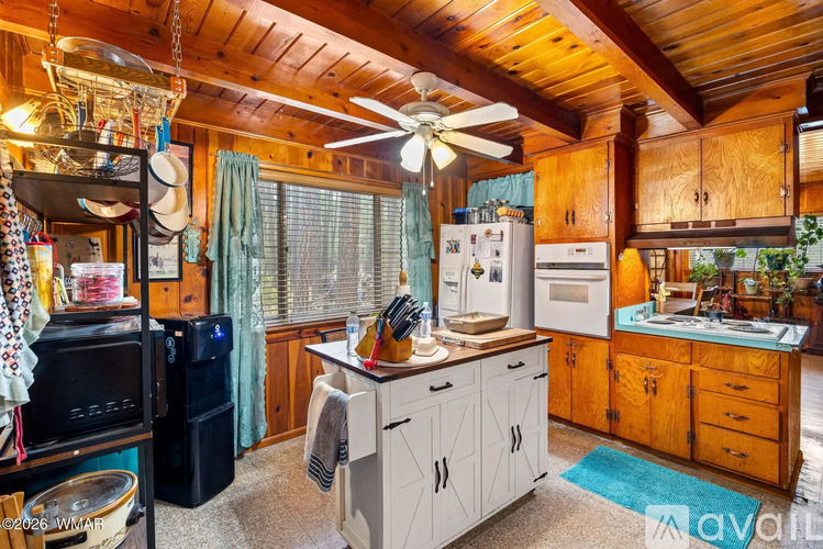 A kitchen with wooden cabinets and a ceiling fan.