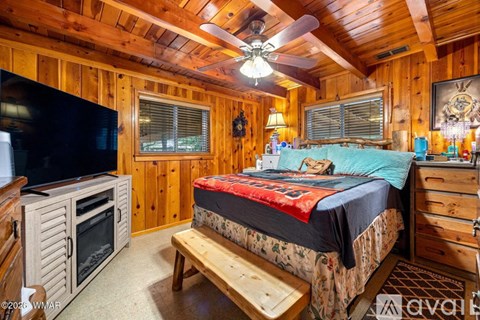 A bedroom with a bed, a bench, and a TV.