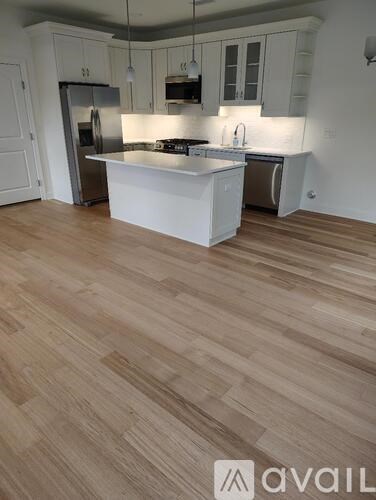 A kitchen with a white island and wooden flooring.