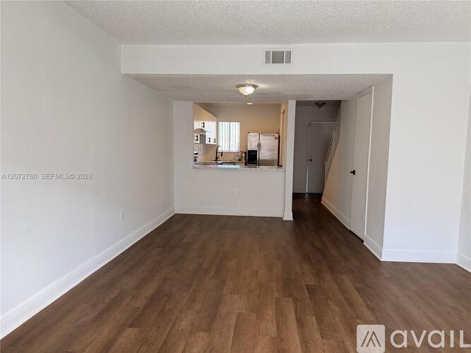 A spacious room with wooden flooring and white walls.