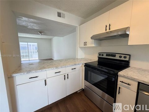 A kitchen with white cabinets and a stainless steel stove top oven.