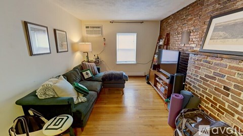 A living room with a green couch and a brick wall.