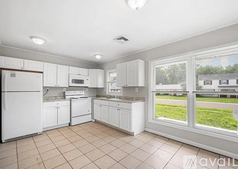 A kitchen with white appliances and cabinets is available for rent.