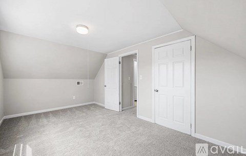 A spacious room with a carpeted floor and two doors.