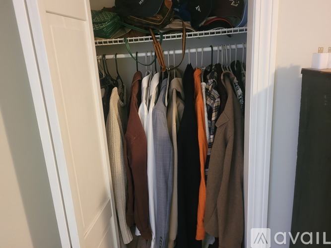 Clothes hanging on a rack in a closet.