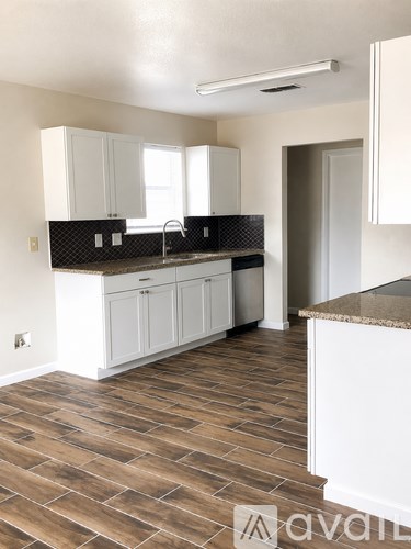 A kitchen with white cabinets and a brown tile floor.