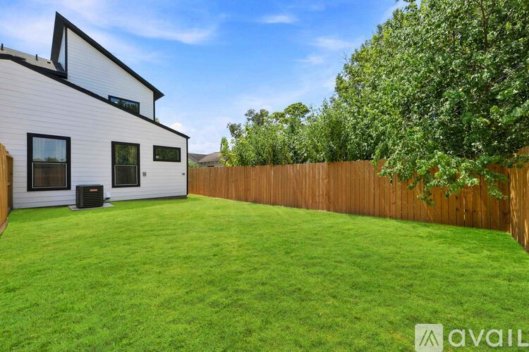 A white house with a wooden fence and green grass in front.