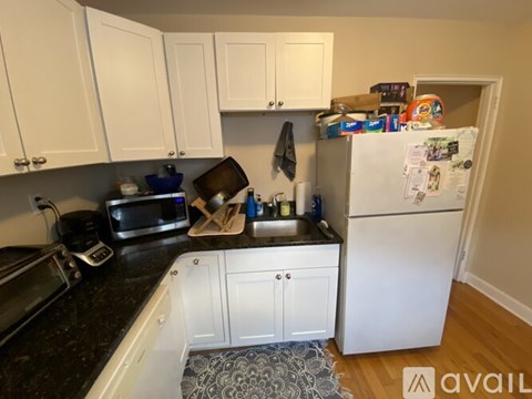 A kitchen with white cabinets and a black countertop.