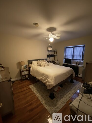 A bedroom with a bed, a ceiling fan, and a window with curtains.