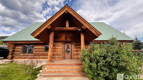 A wooden cabin with a green roof and a wooden door.